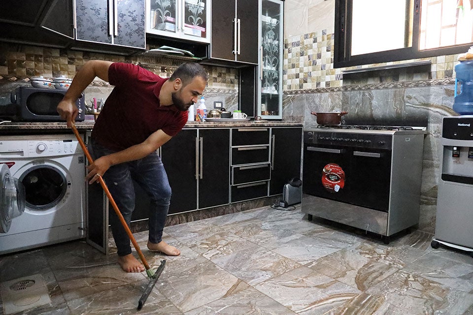 اللاجئ الفلسطيني، محمود شراري يساعد في الأعمال المنزلية في منزله في مخيم الرشيدية في لبنان أثناء عمل زوجته. هيئة الأمم المتحدة للمرأة/ دار المصور